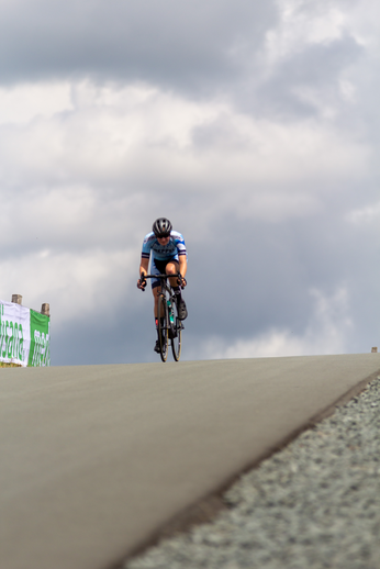 A cyclist wearing a blue jersey is riding on a hill.