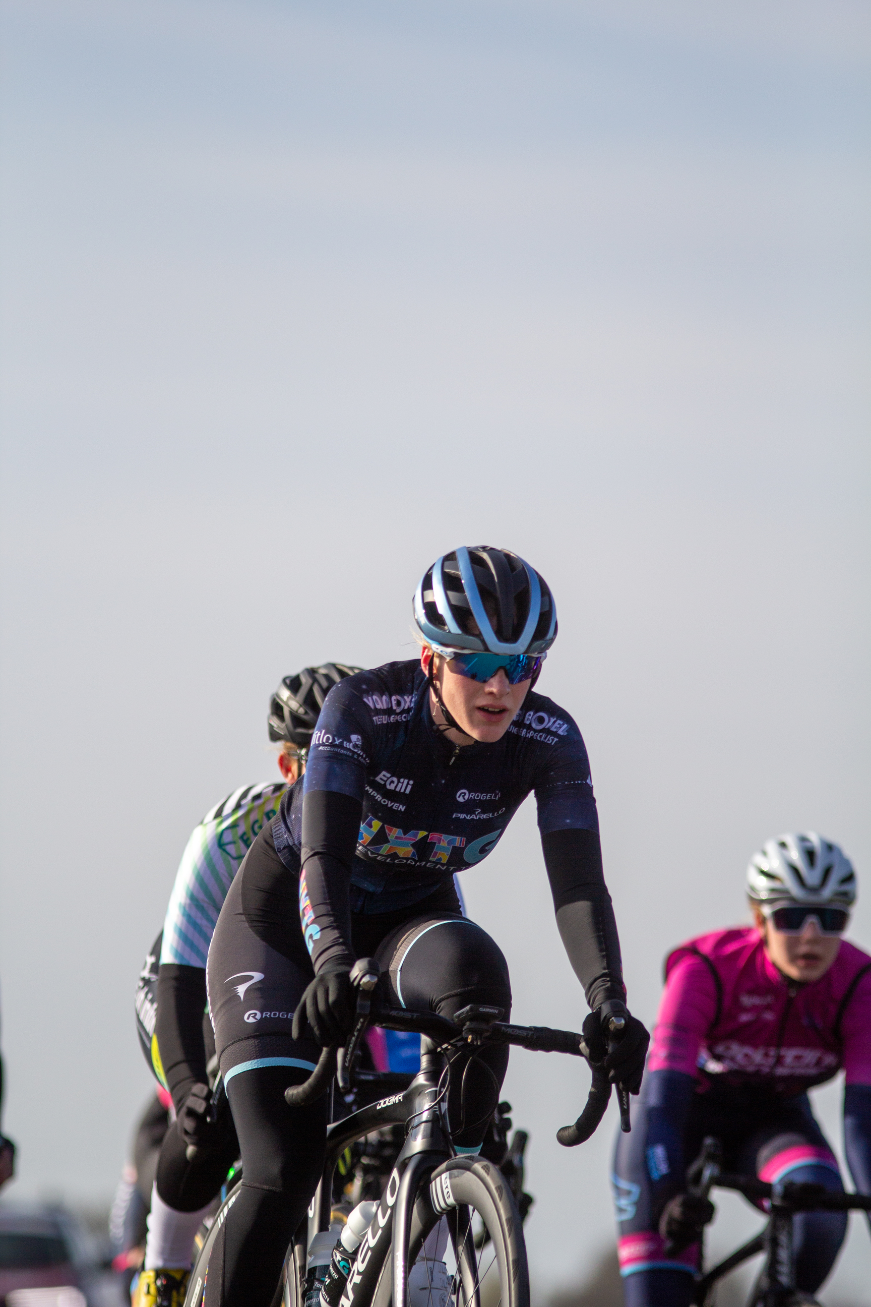 Three cyclists racing in a field during the Noord West Overijssel dames event in 2022.