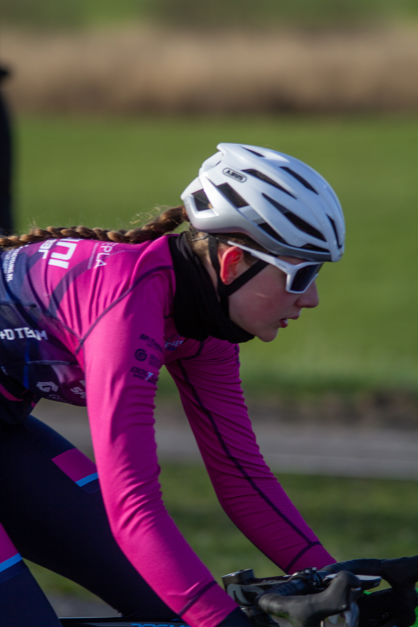 A woman in a pink jersey with a blue number 1. She has a white helmet and is riding a bike.