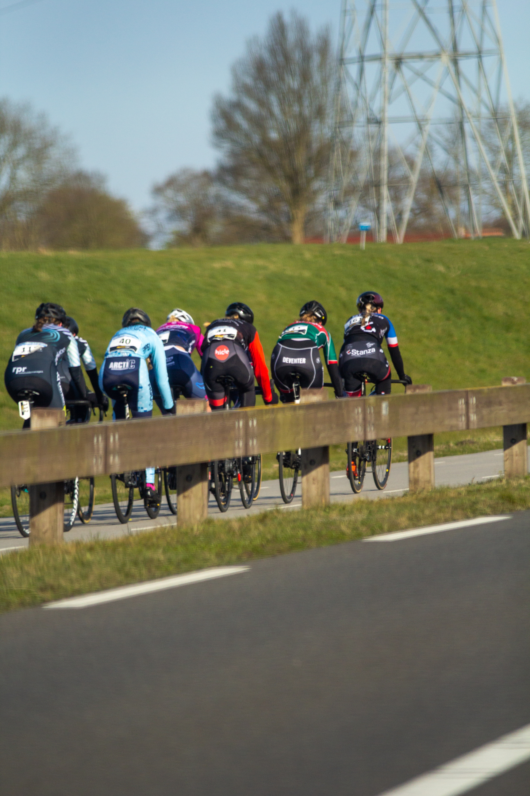 A group of cyclists riding down a hill wearing jerseys with the word Wielrennen on them.