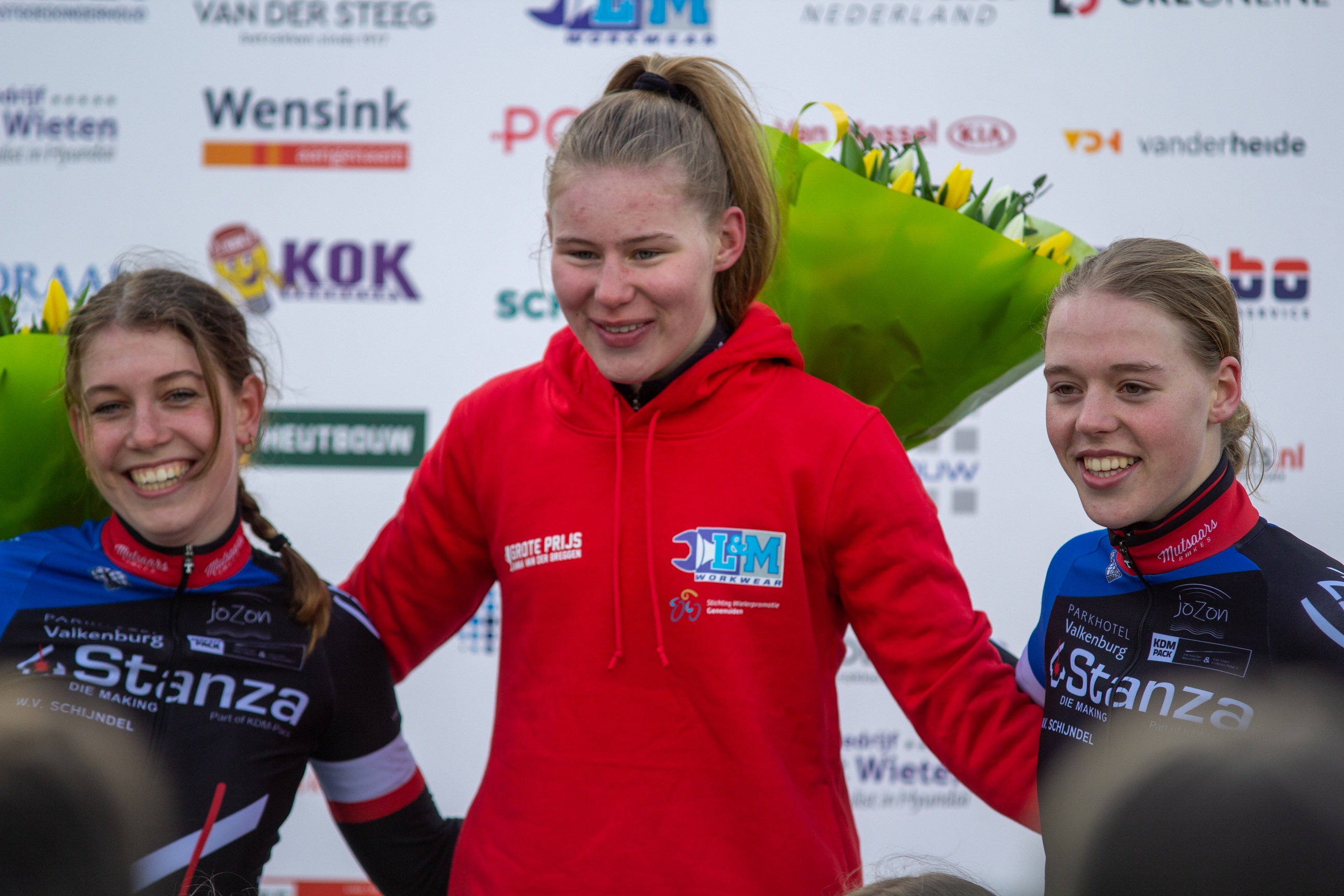 Three women wearing red and blue jerseys, smiling at the camera.