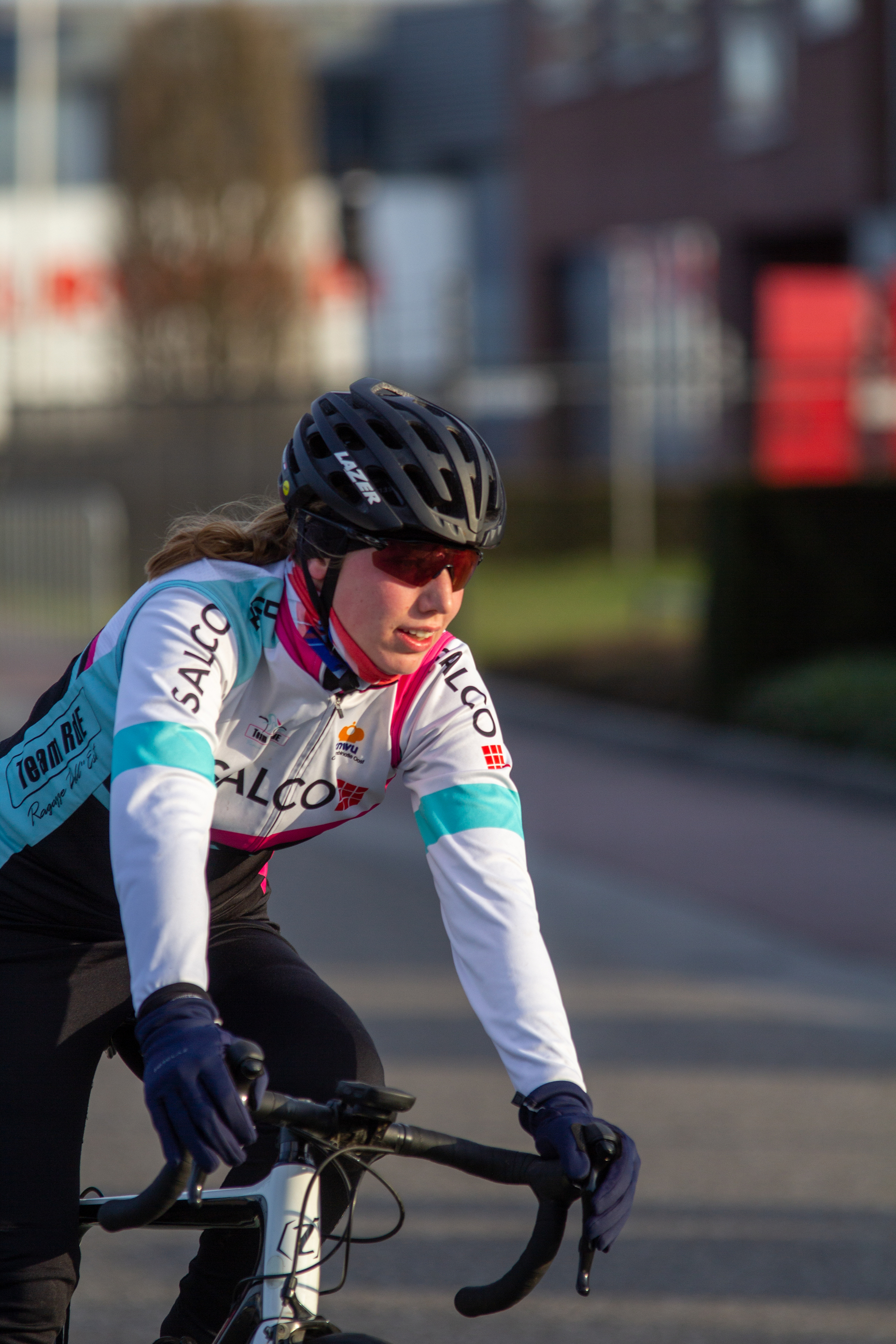 A woman wearing a pink helmet is riding her bicycle.