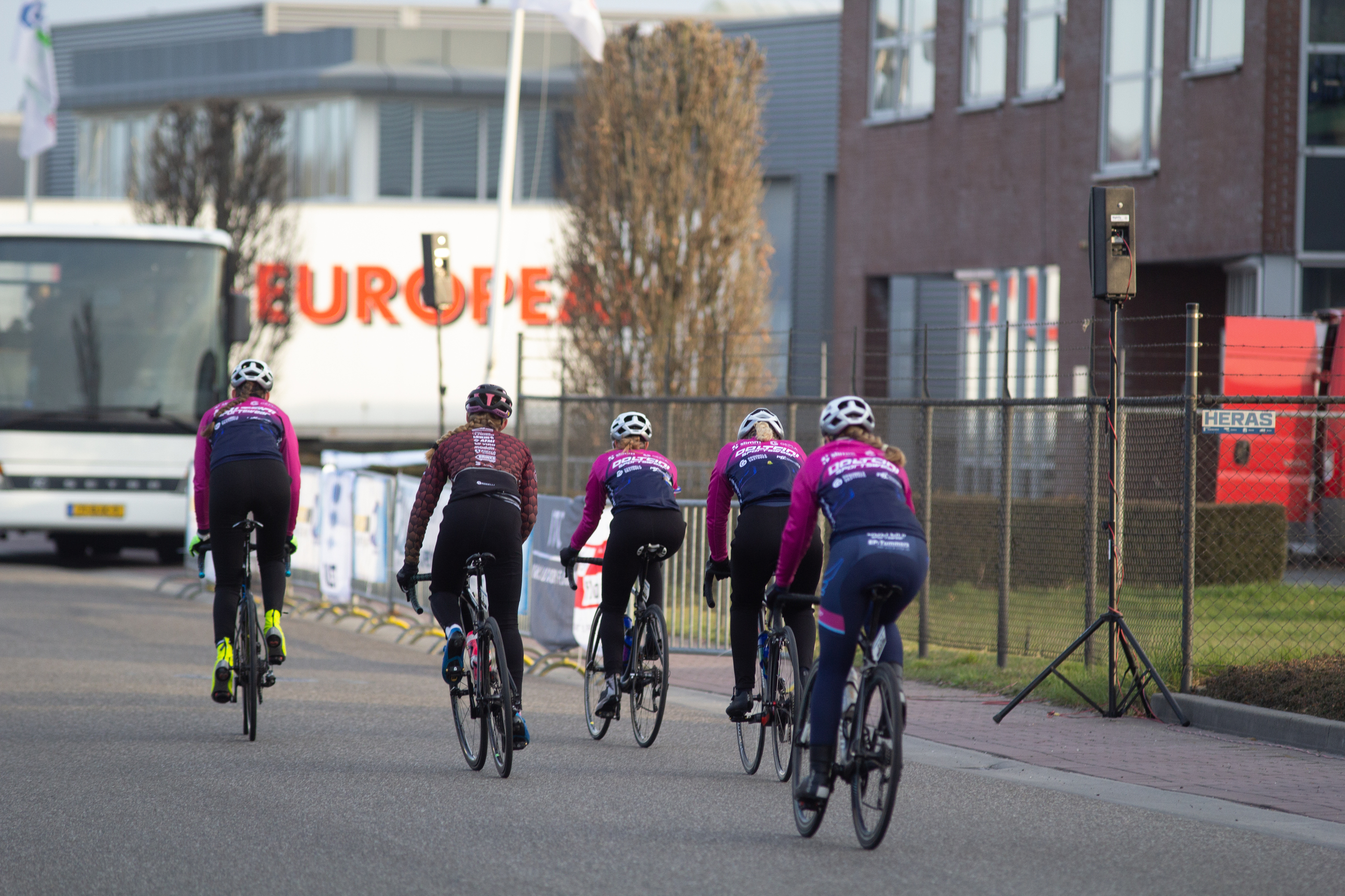 Four female cyclists on a street with one wearing a purple shirt saying NWO Dames.