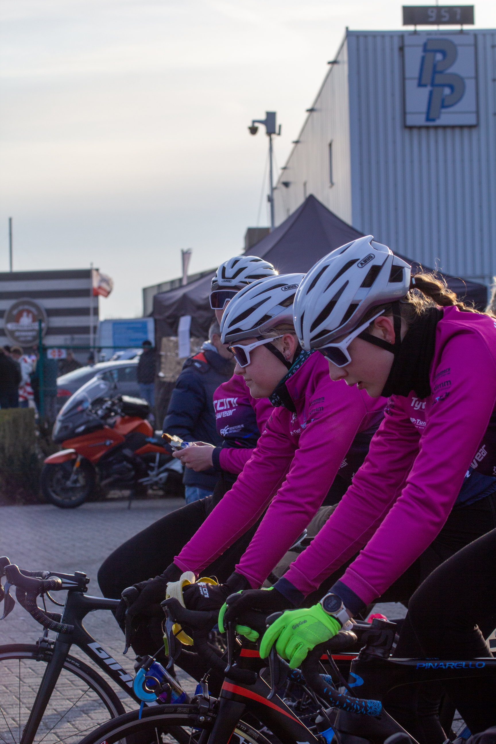 A woman wearing a pink shirt is riding a bike with three other women.