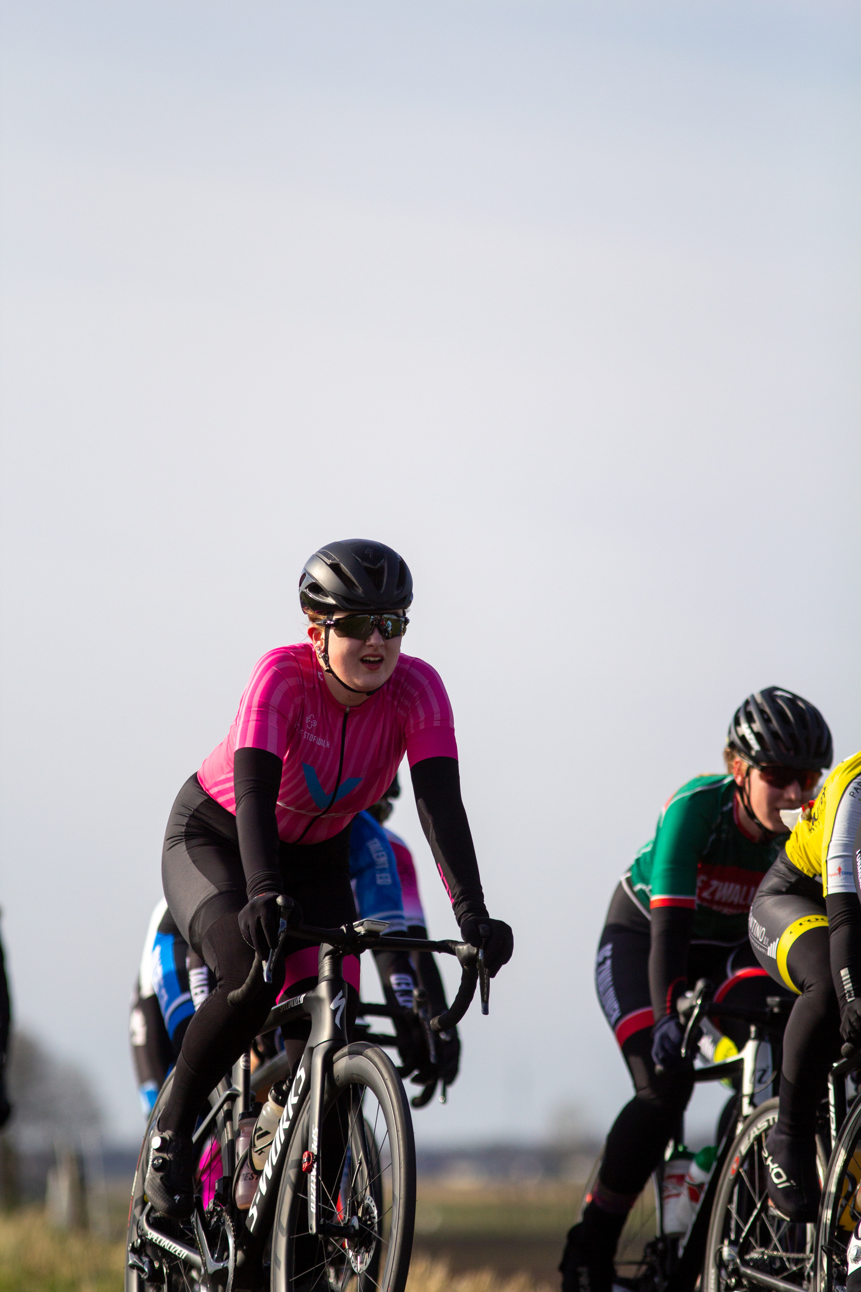 Women wearing helmets riding bikes with colored tops.