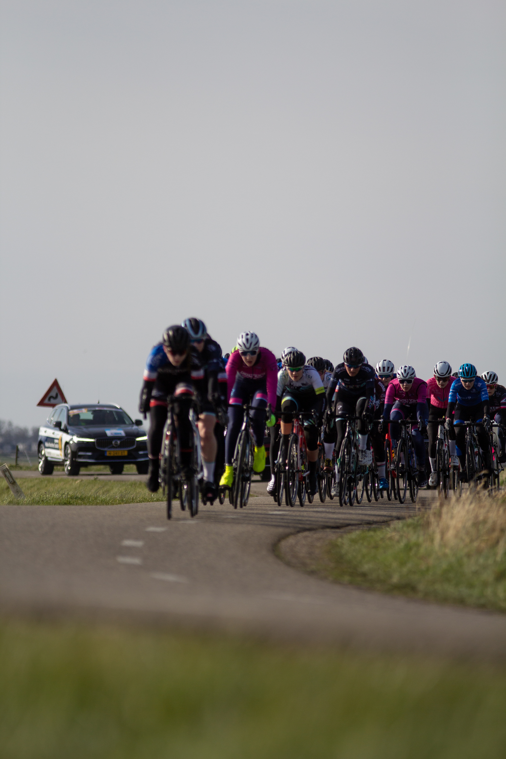 Several people ride their bikes in a race across the street.