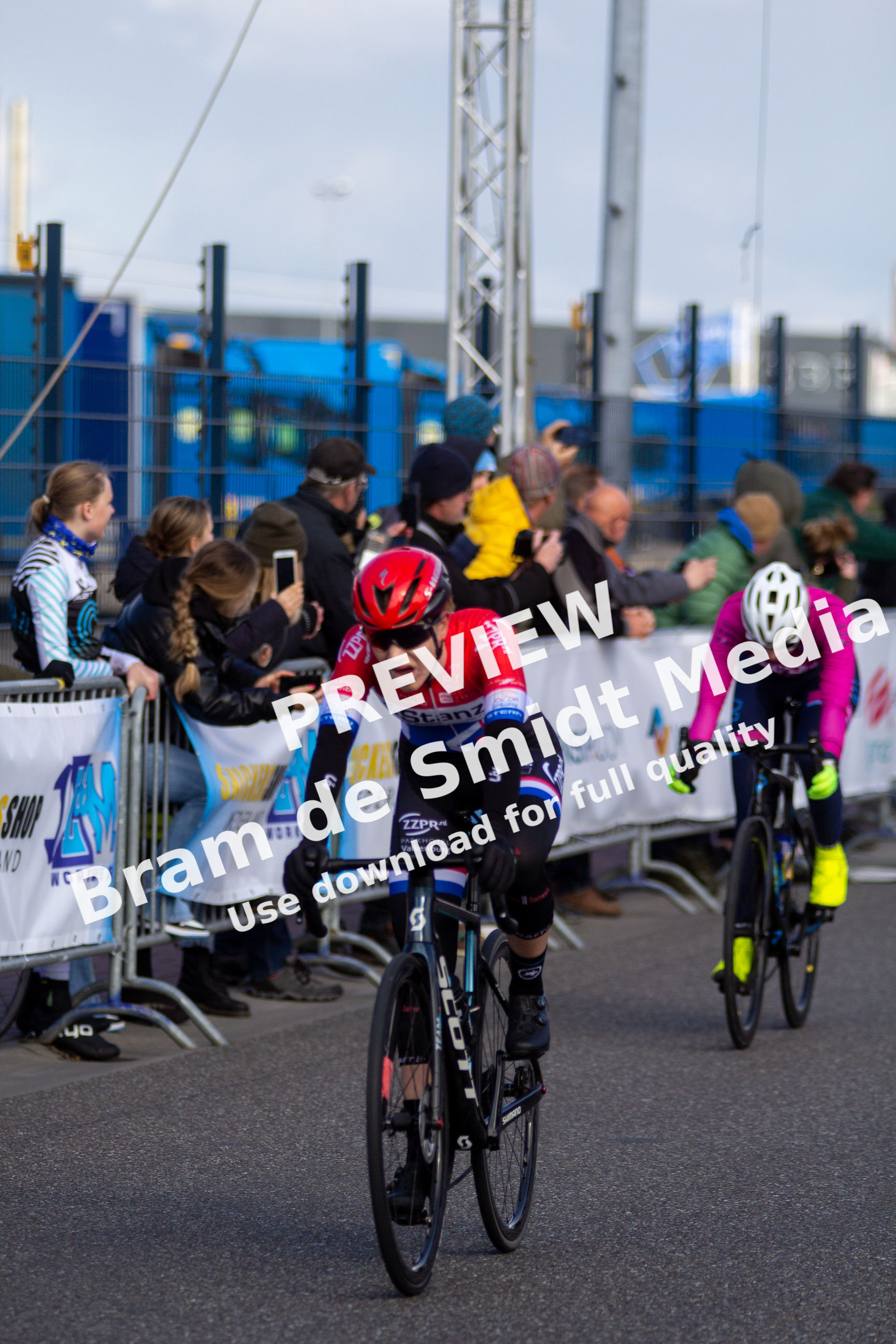 Two cyclists compete in a race, representing different teams and their sponsors.