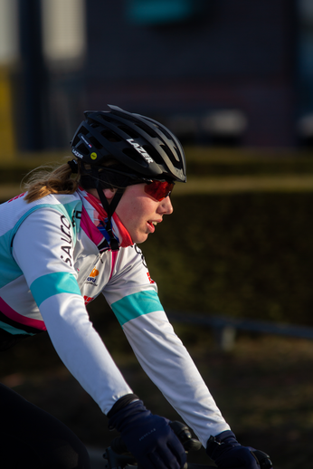 A female cyclist wearing sunglasses, a helmet and riding a bike.