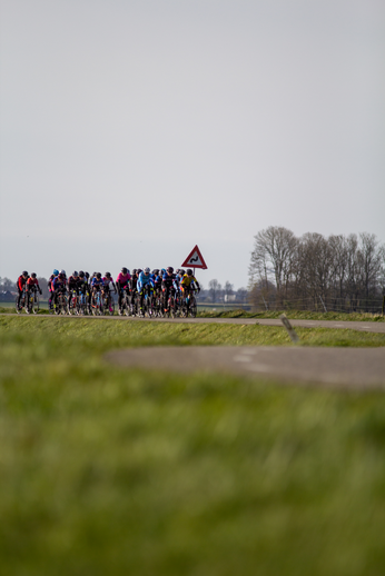 A group of people riding bicycles down a road with a red sign that says Stop.