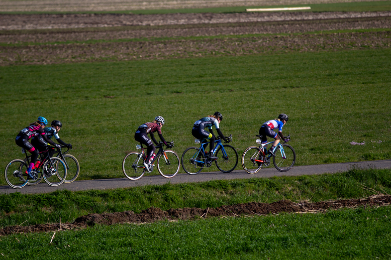 Three cyclists riding in a line in the countryside.