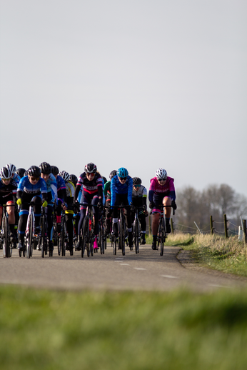 A group of cyclists wearing colorful clothing, on a road in North West Overijssel.