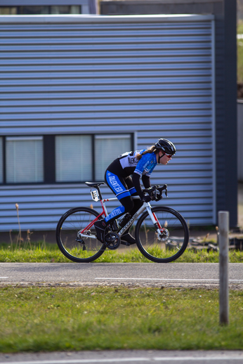 A man in a blue and black suit rides a red and white bike.