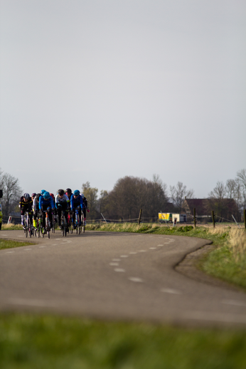 A group of bicyclists ride down a road during the Noord West Overijssel Dames race.