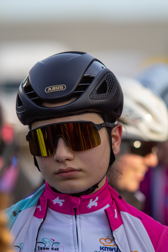 A young person wearing a bike helmet, sunglasses, and a cycling shirt.