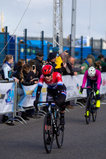 Two cyclists compete in a race, representing different teams and their sponsors.