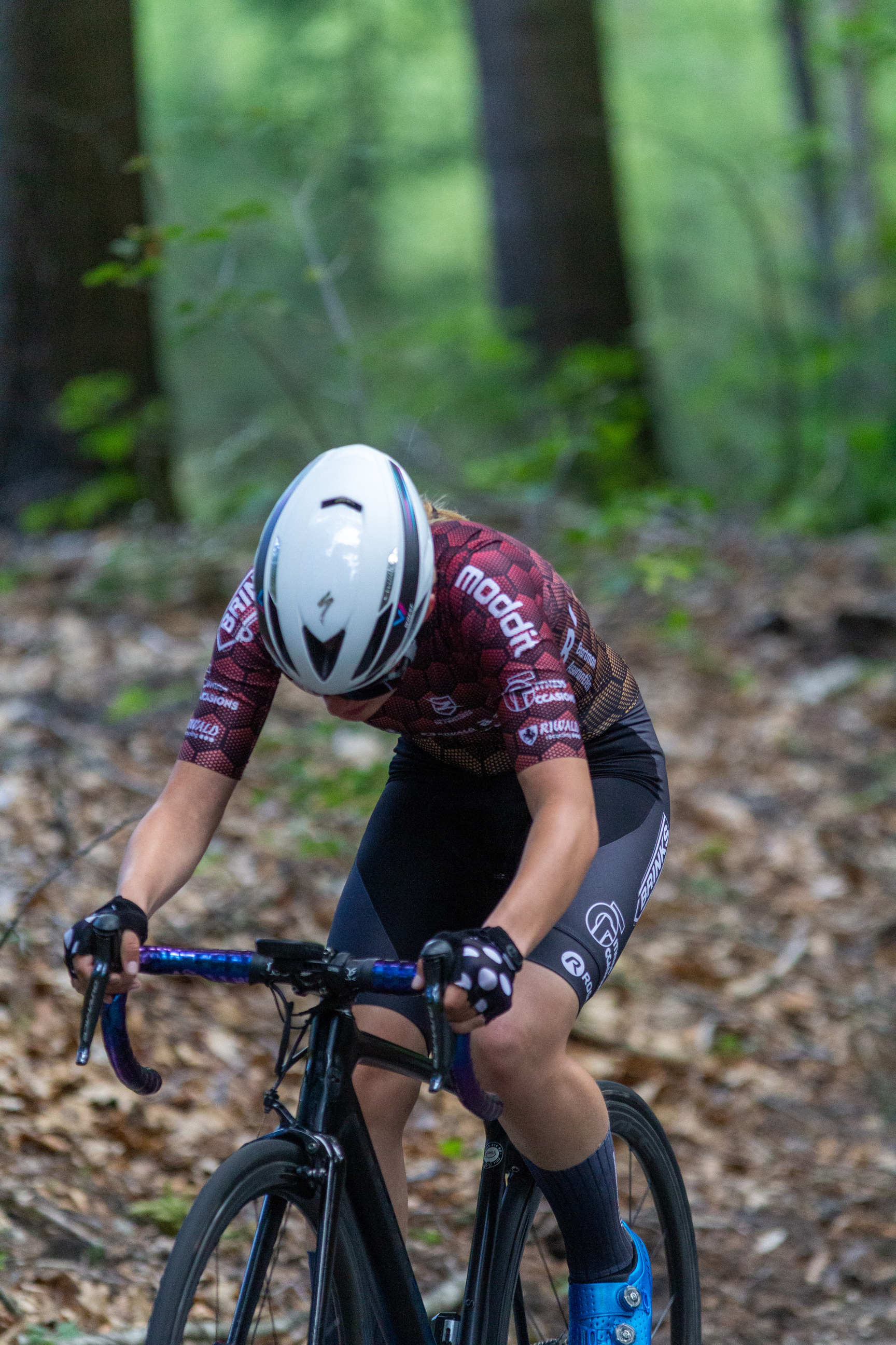 A person wearing a red and black Wielrennen shirt riding a bike.