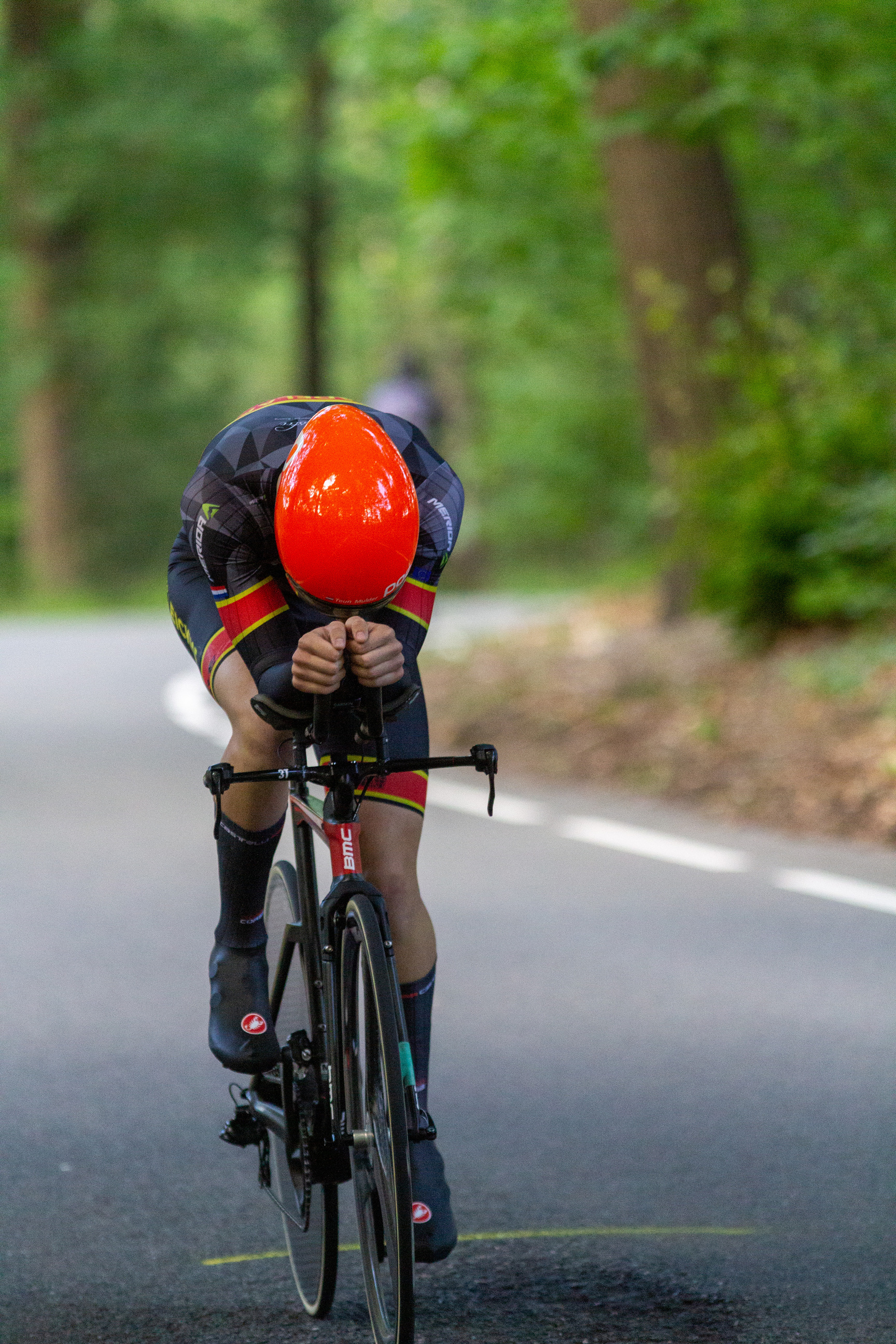 A person riding a bicycle while wearing a red helmet and uniform.