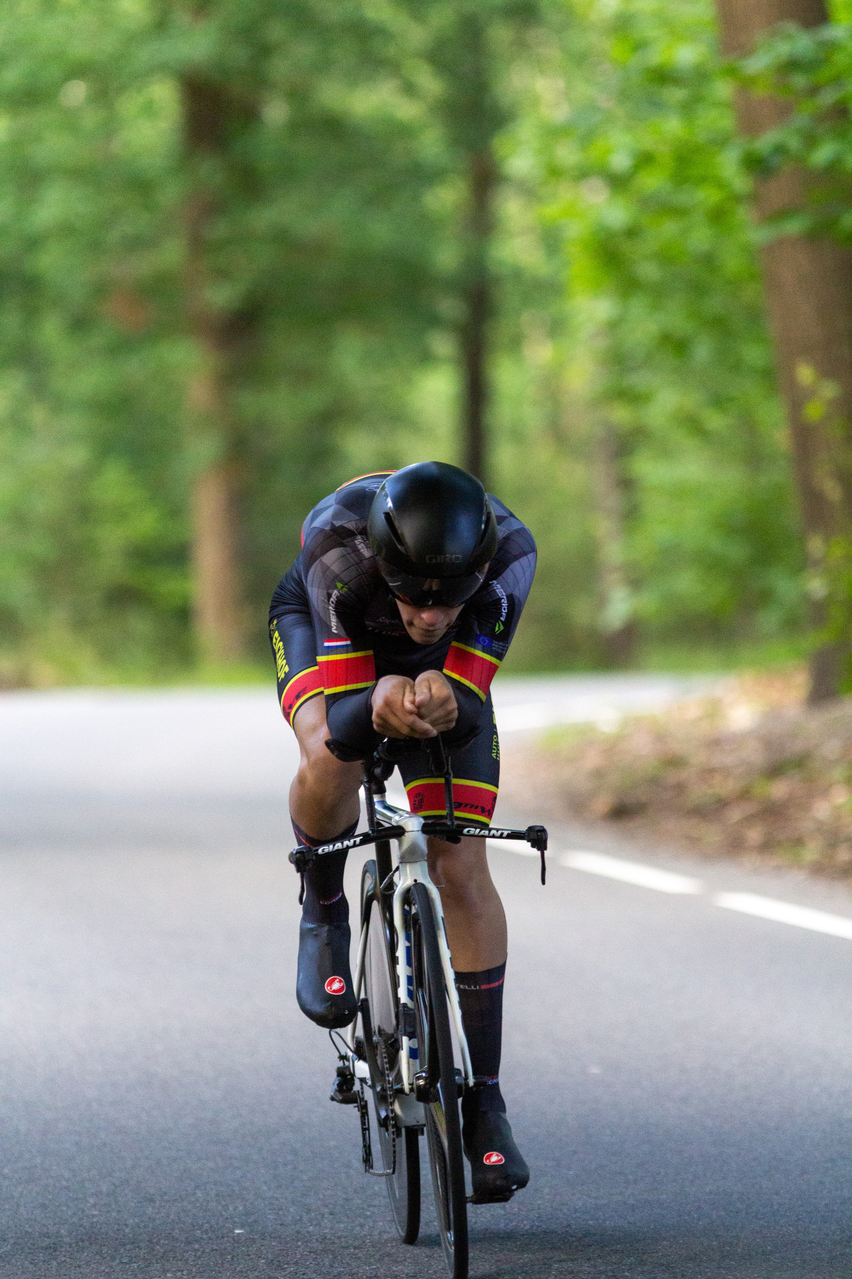 A cyclist wearing a black helmet is riding a bicycle on the side of a road.