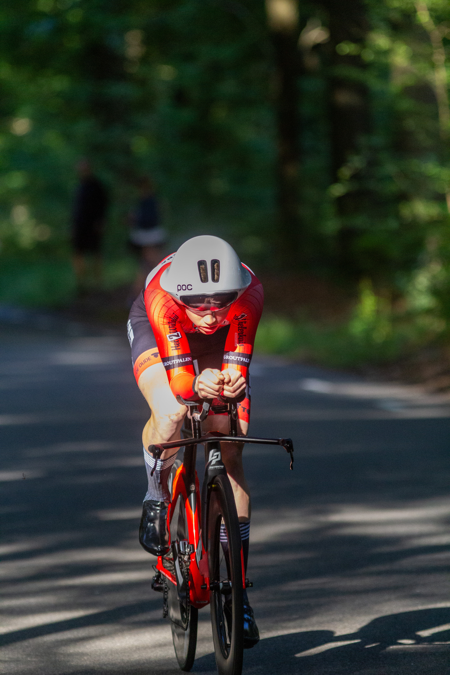 A person wearing a red outfit with number 9 on it is riding a bicycle.