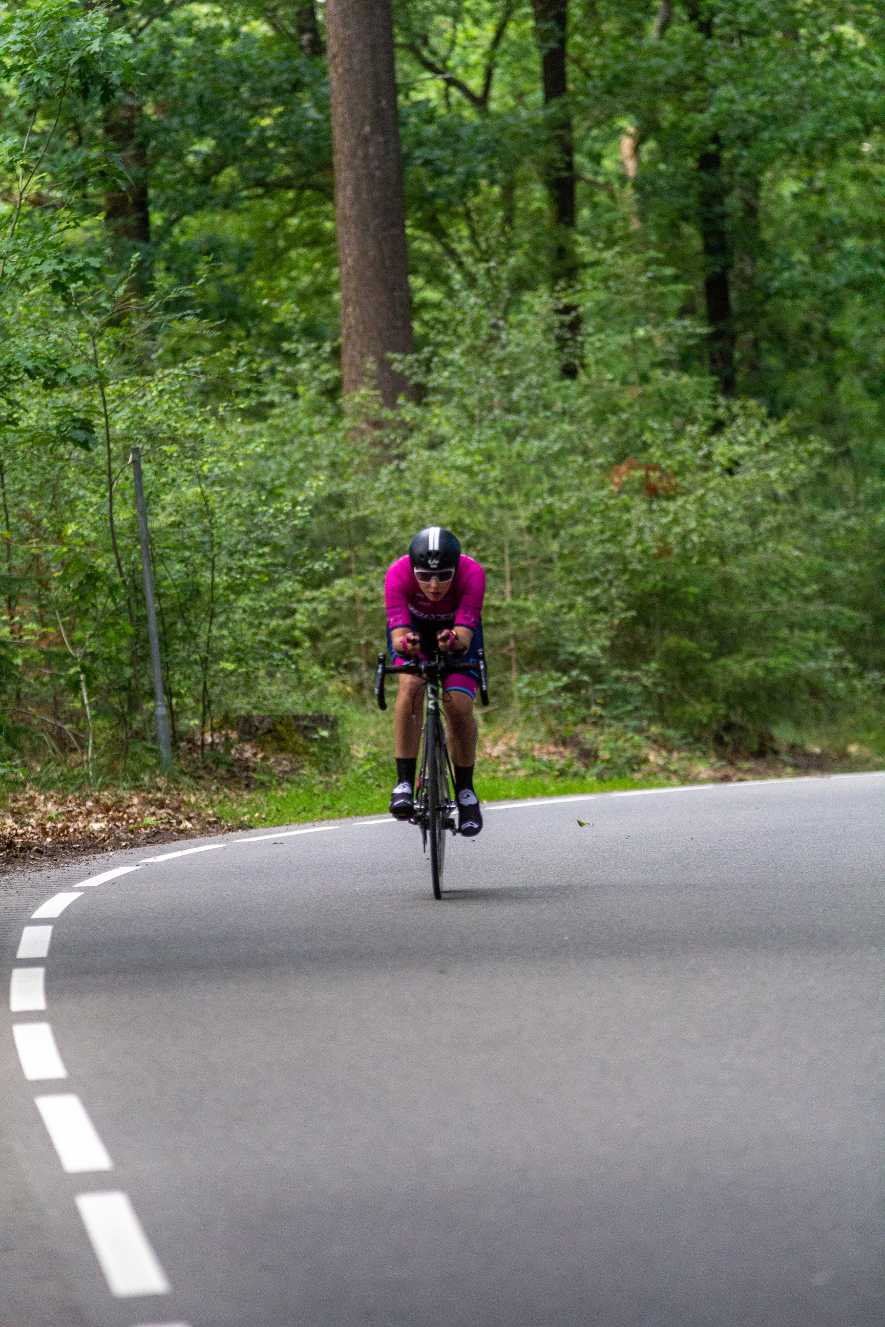 A person in a purple shirt rides a bike on the road.