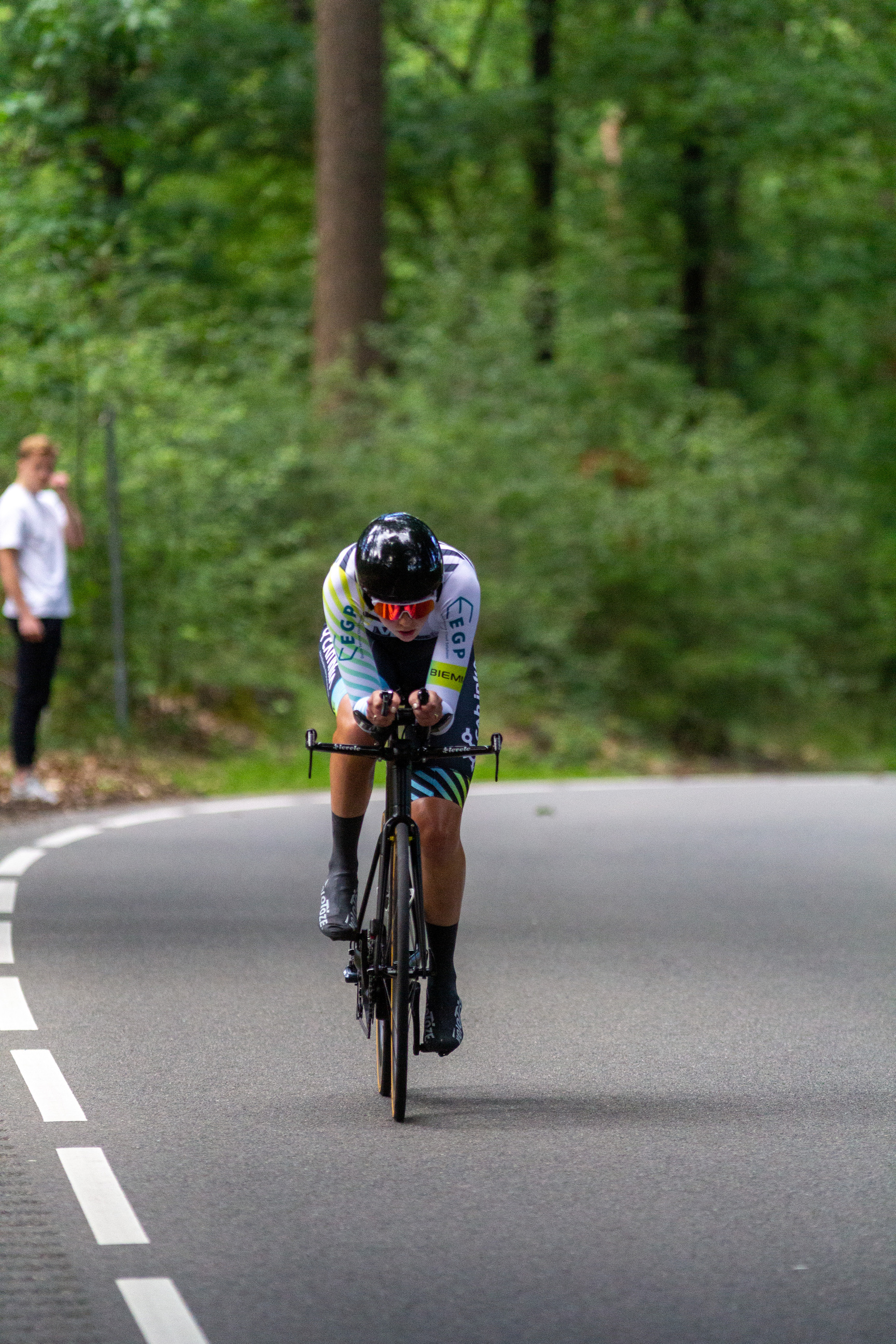 A bicycle racer wearing a number 4 jersey is riding down a road.