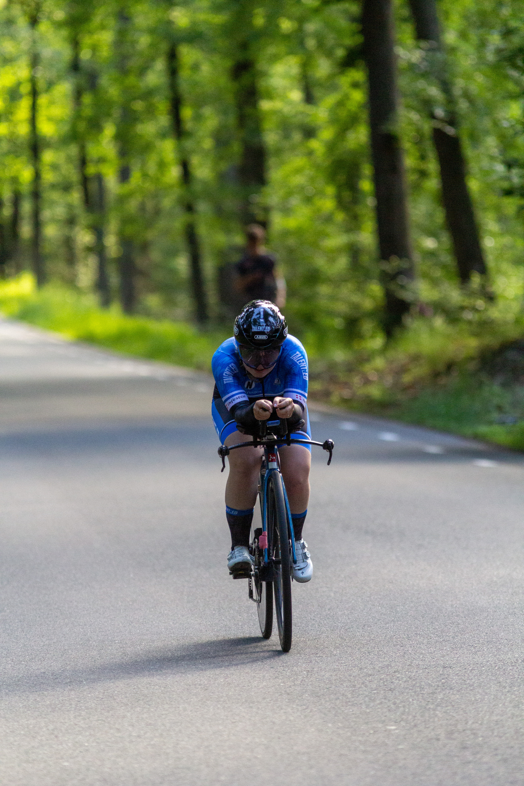 A person is riding a bike down the road in a blue outfit.