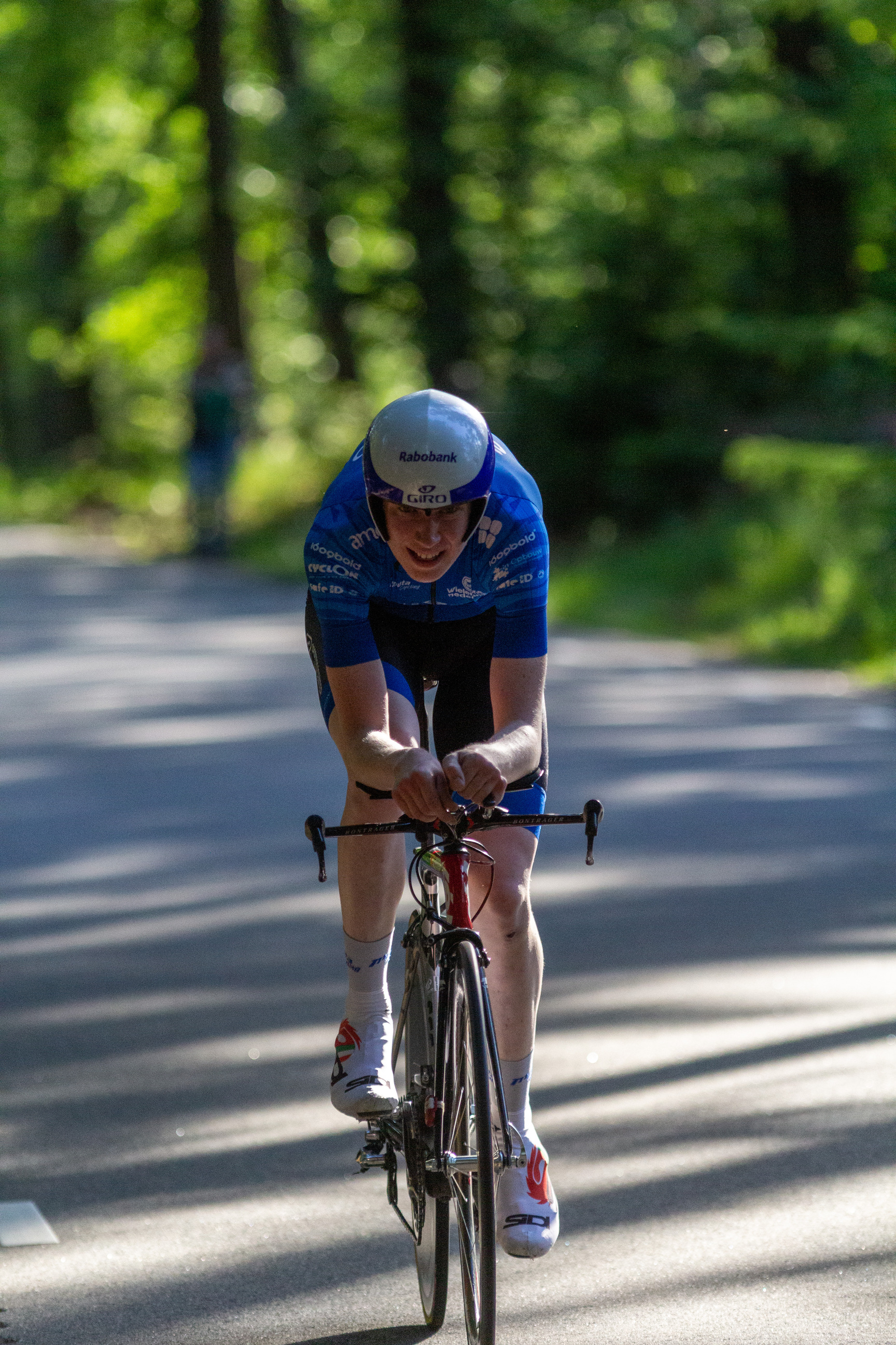 A cyclist in a blue uniform is riding on the road.