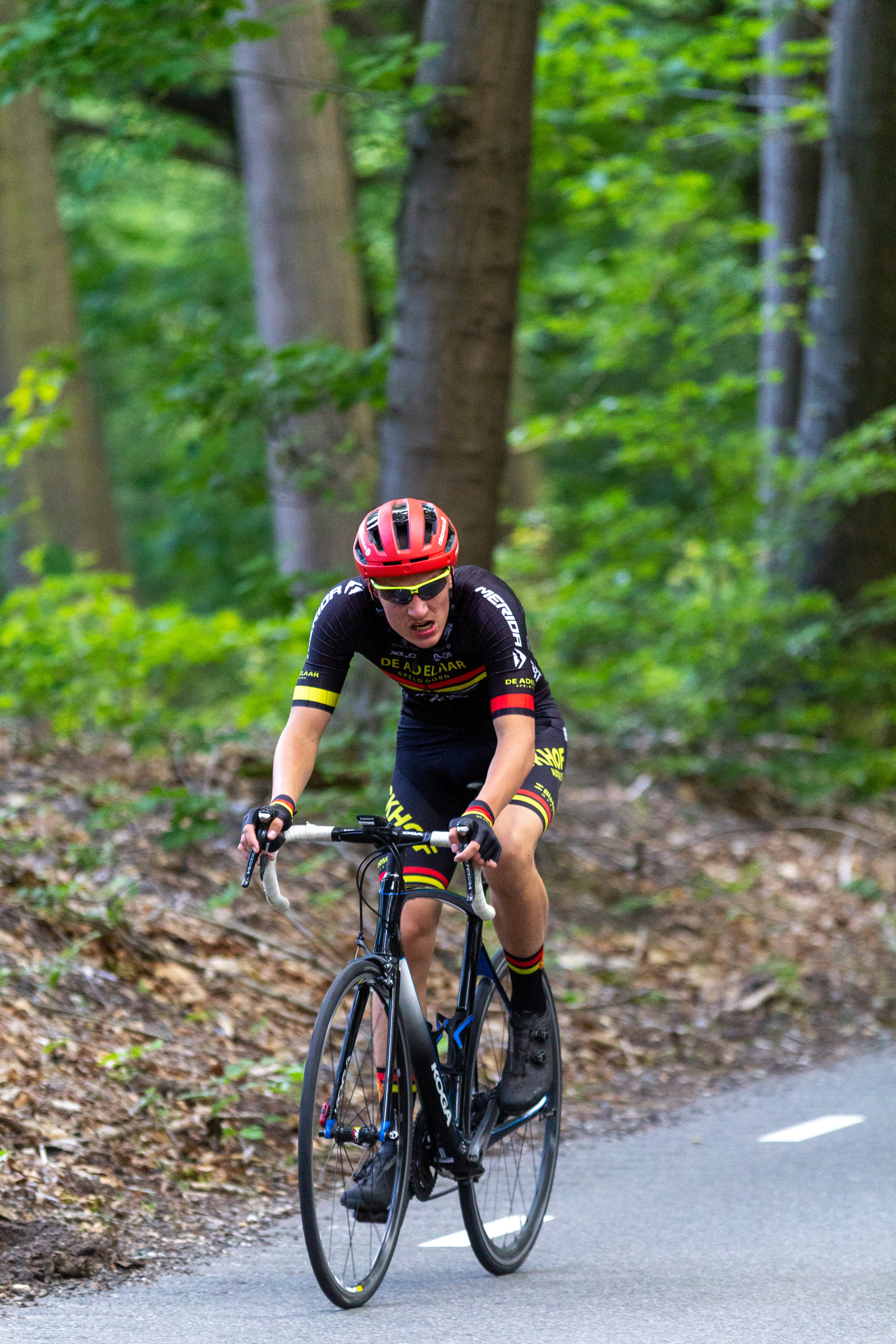 A cyclist is wearing a helmet and racing on a street.