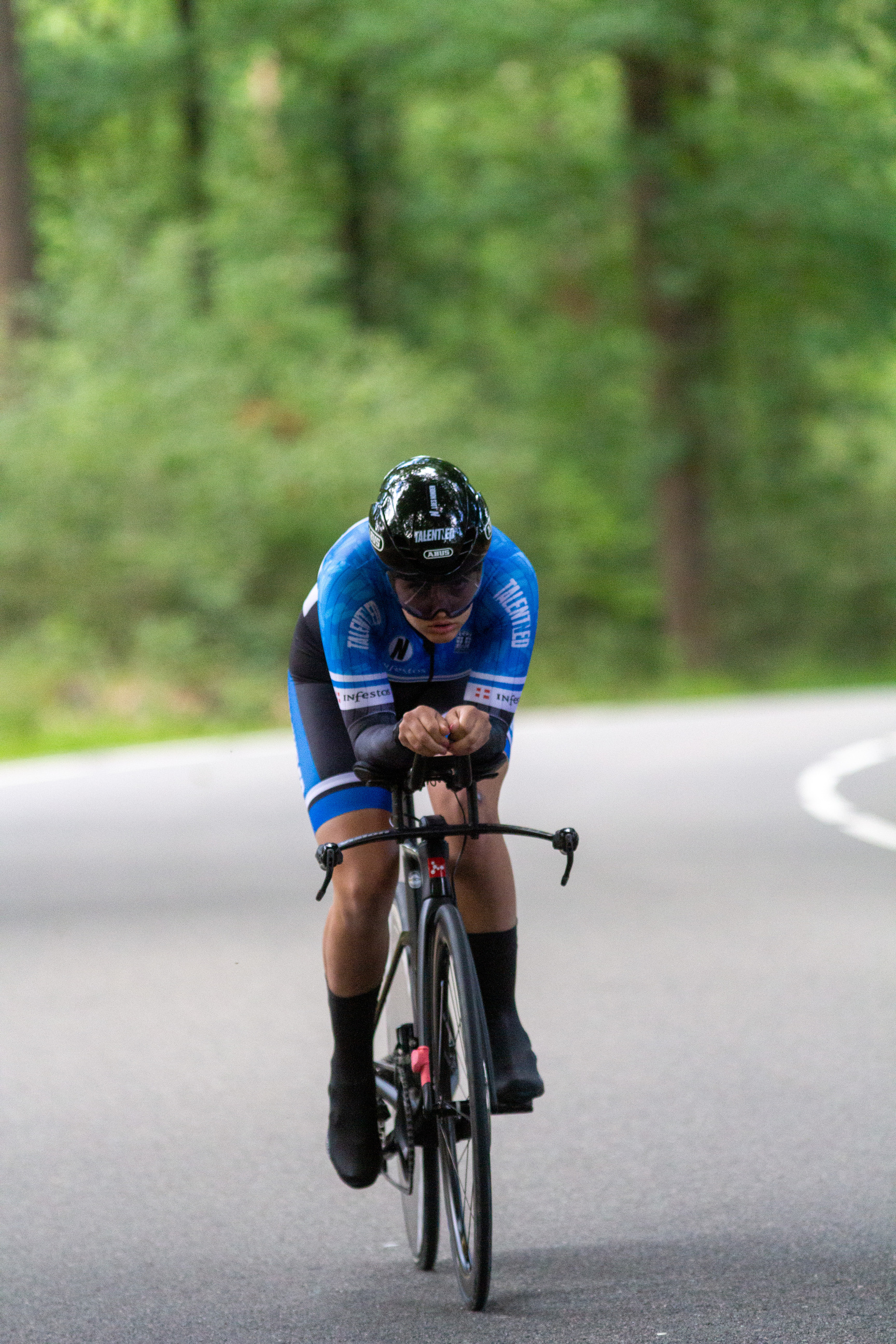 A man in a blue and black racing suit is riding a bicycle.