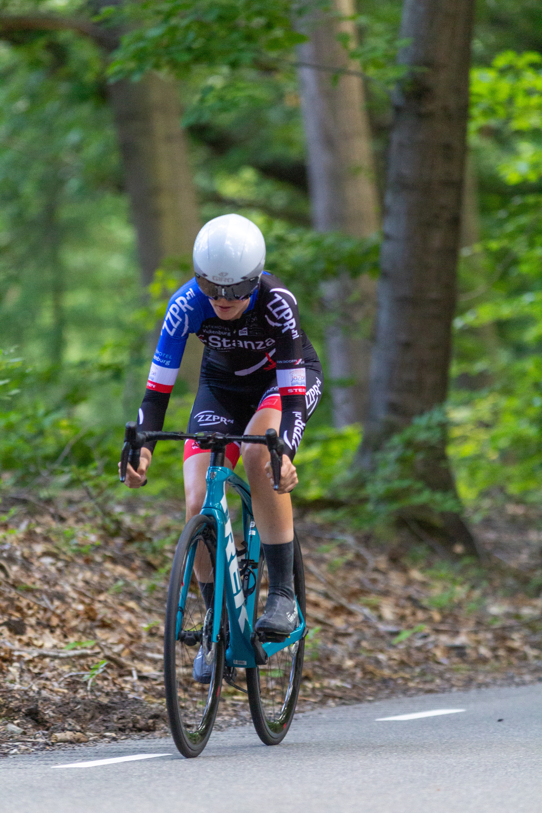 A cyclist in black and blue uniform riding on a bike.