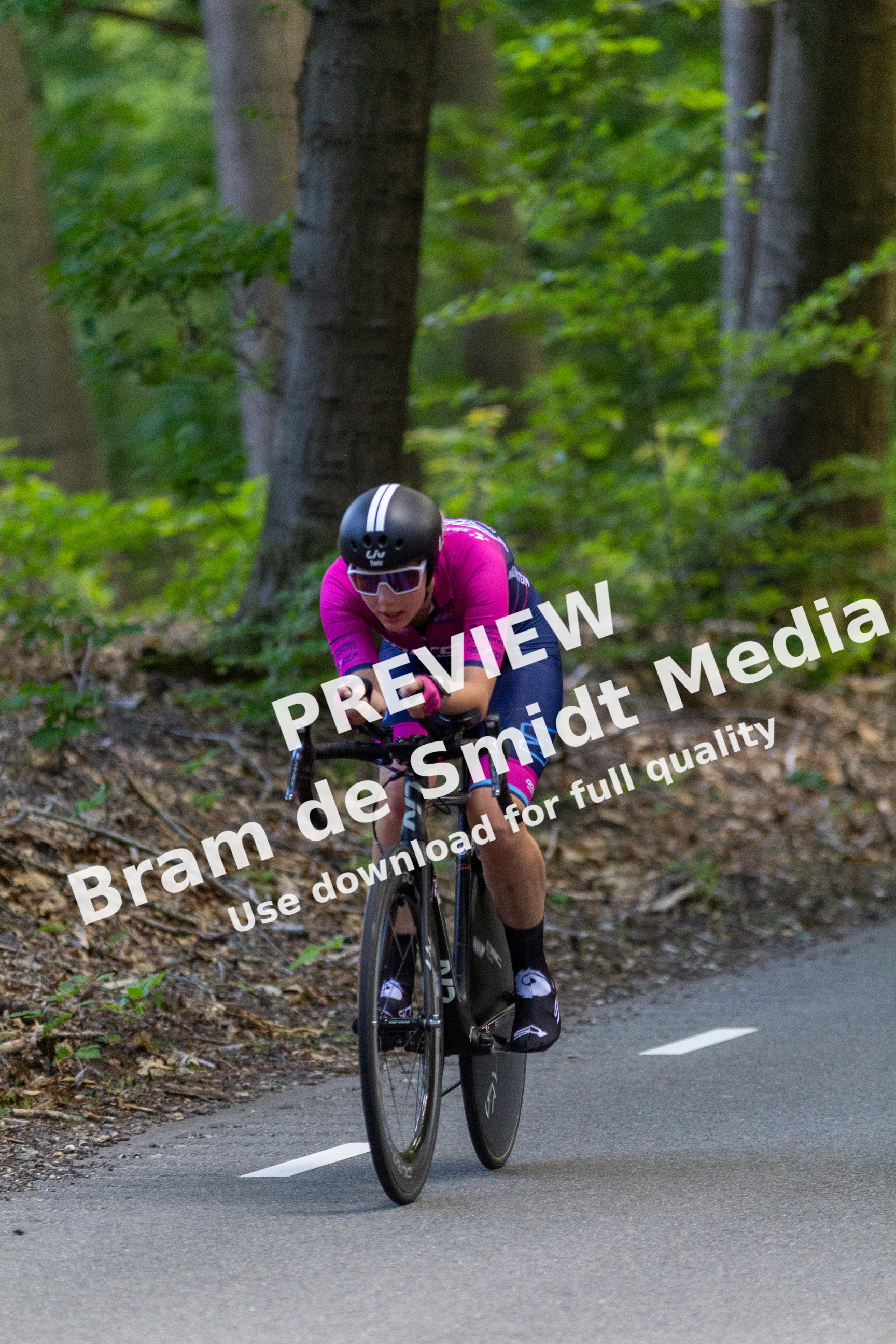 A cyclist dressed in pink jersey and blue pants is on the track with a bicycle.