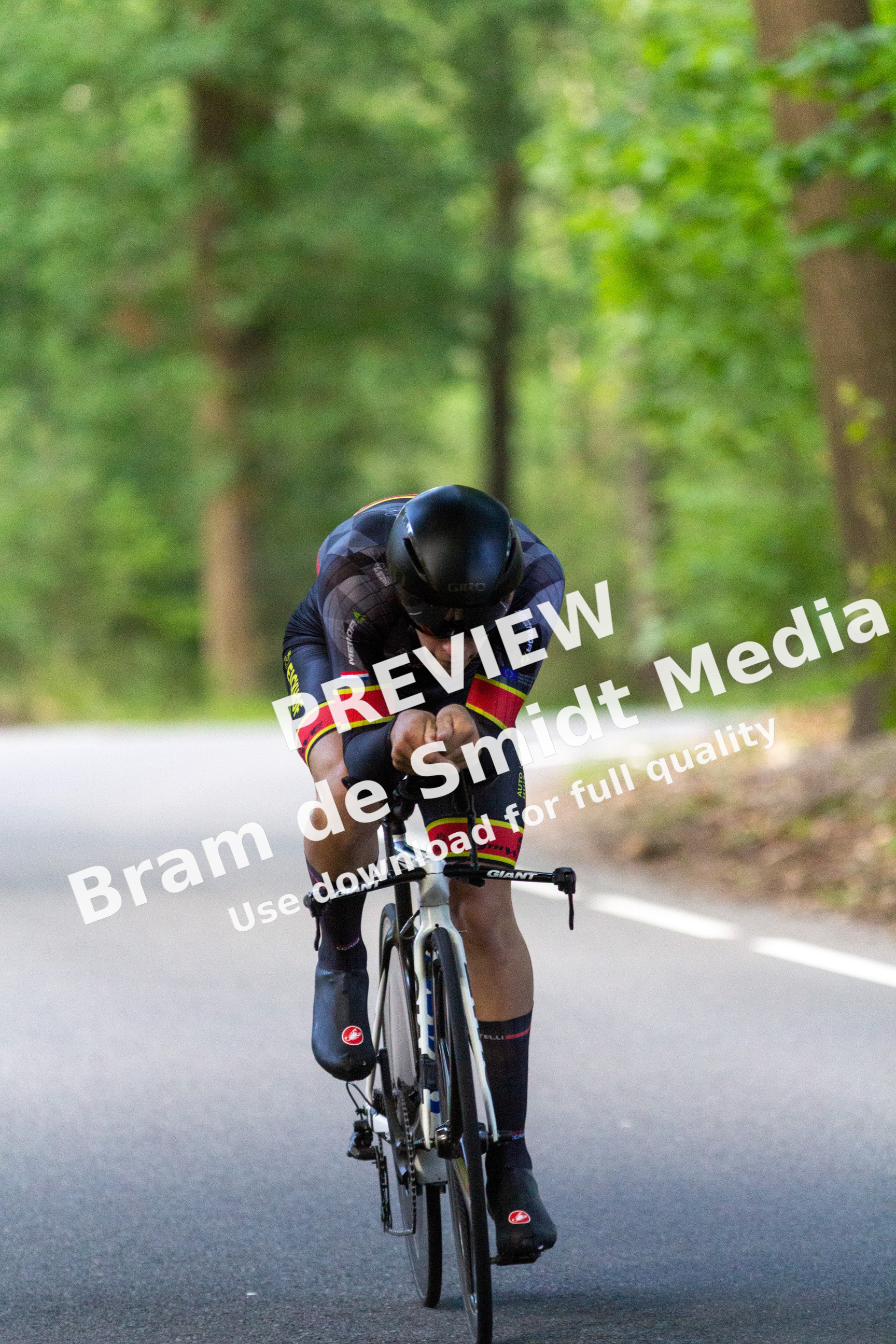 A cyclist wearing a black helmet is riding a bicycle on the side of a road.