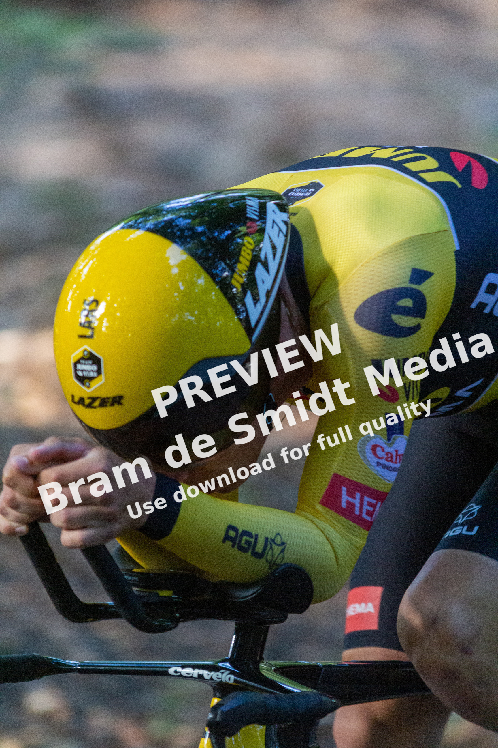 A yellow and black bicycle racer, number 2, is leaning forward over the handle bars as he races.