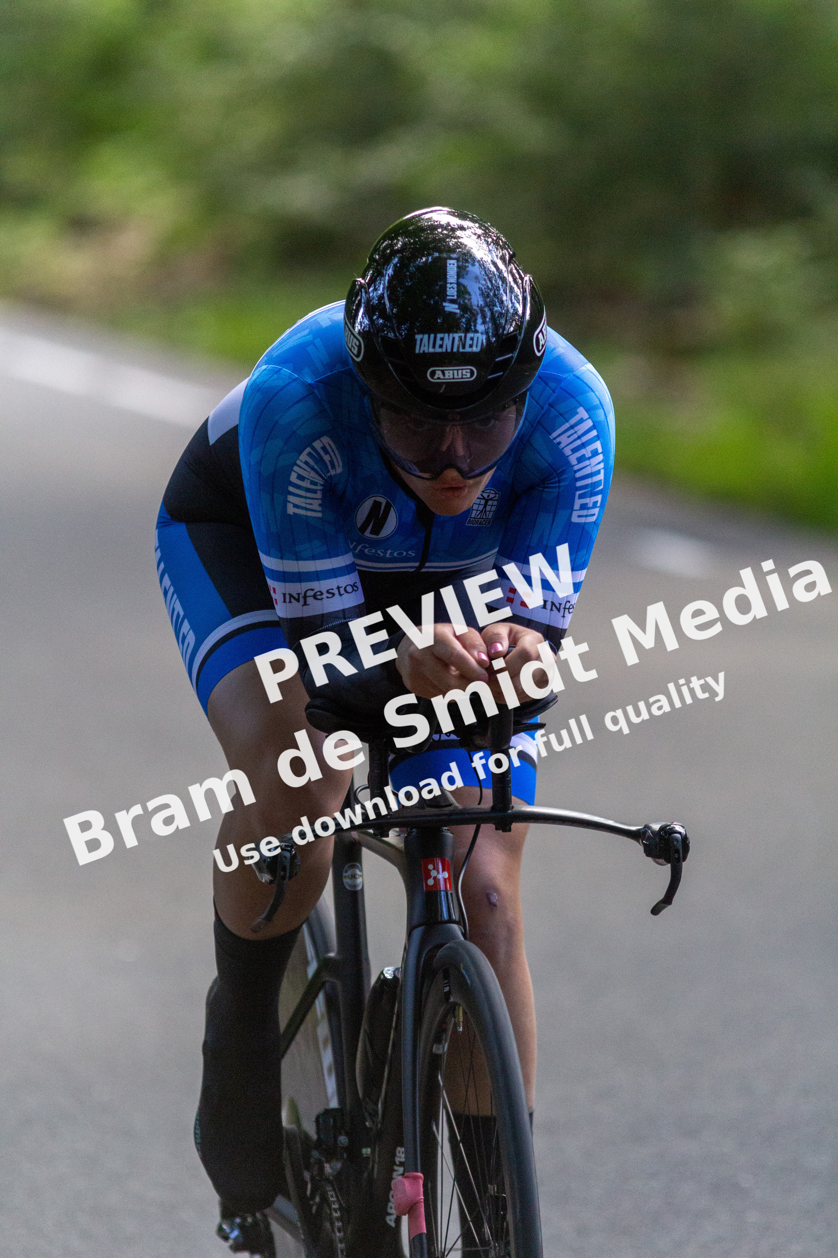 A man in a blue cycling suit is riding his bike on the street.