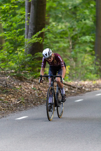 A man wearing a blue and white helmet riding a bicycle on the road.