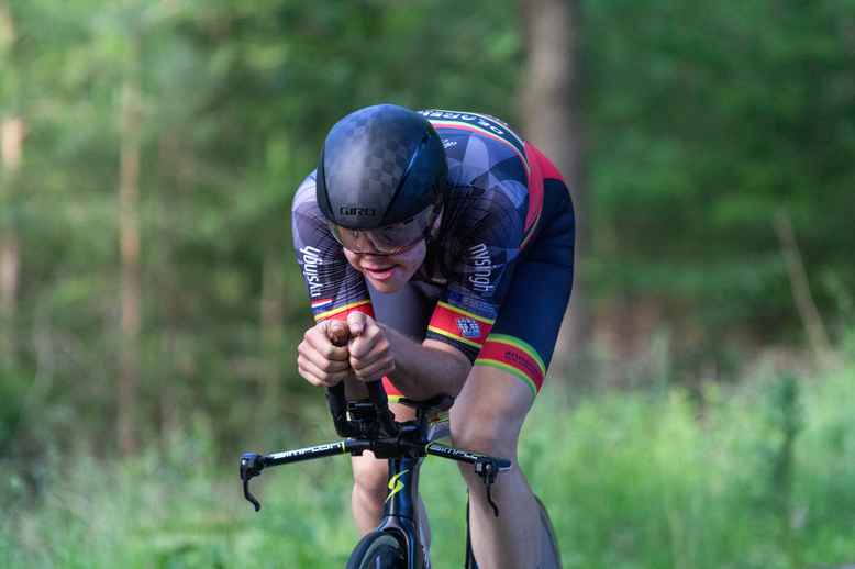 A cyclist wearing a blue and red jersey riding on a black bicycle.