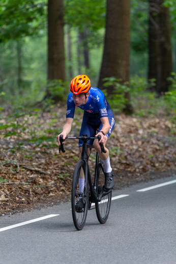 A person in a blue and white jersey is riding a bike down the street.