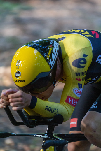 A yellow and black bicycle racer, number 2, is leaning forward over the handle bars as he races.