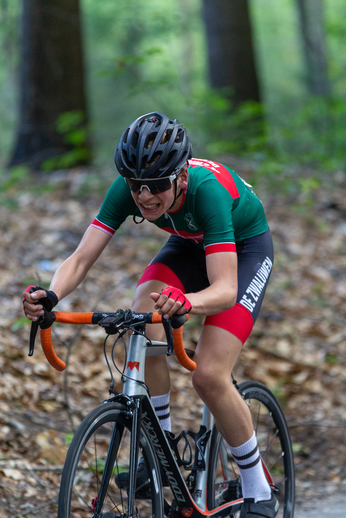 A person in a green shirt and red shorts on a bike with the words "DK Oost" on it.