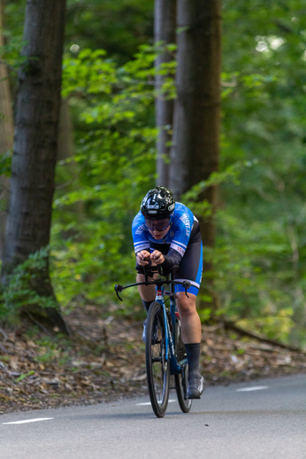 A person wearing a blue shirt and black bike shorts is riding a bicycle.