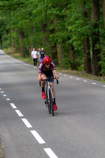 A cyclist racing down a road with the number 6 on his bike.