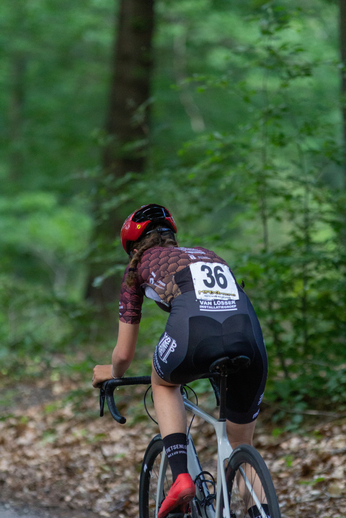 A cyclist with a red helmet is wearing a number 36 shirt.