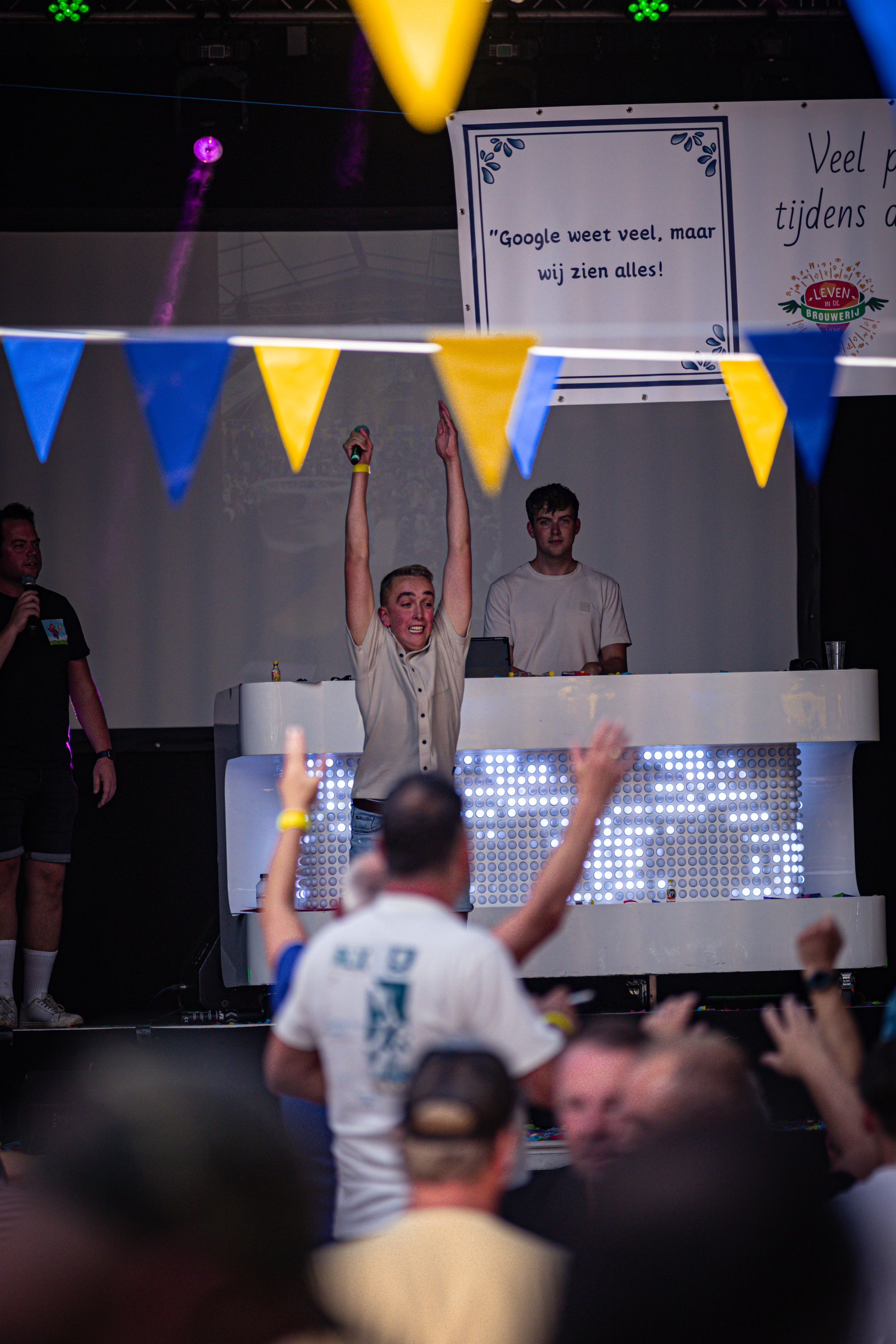 A pub quiz with a DJ on stage in the background is happening.