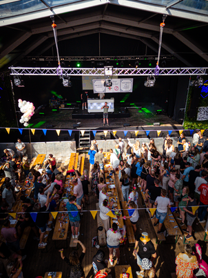 People enjoying a party in an arena with banners hanging from the ceiling that say "Pub Quiz".