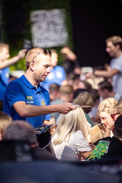 A man gives a pen to another person while standing at an event called Pubquiz.