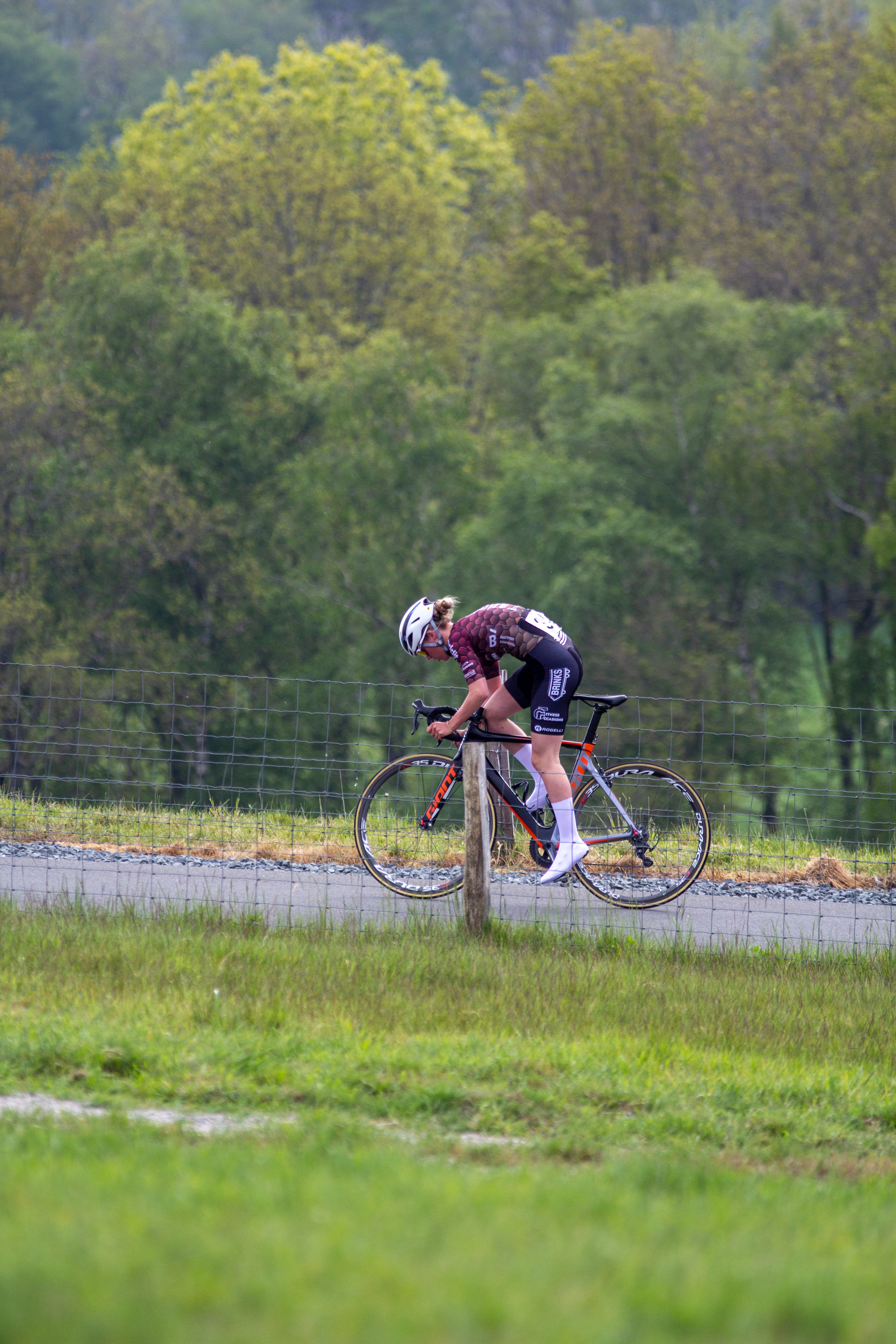 A woman on a bike going down the road during a race.