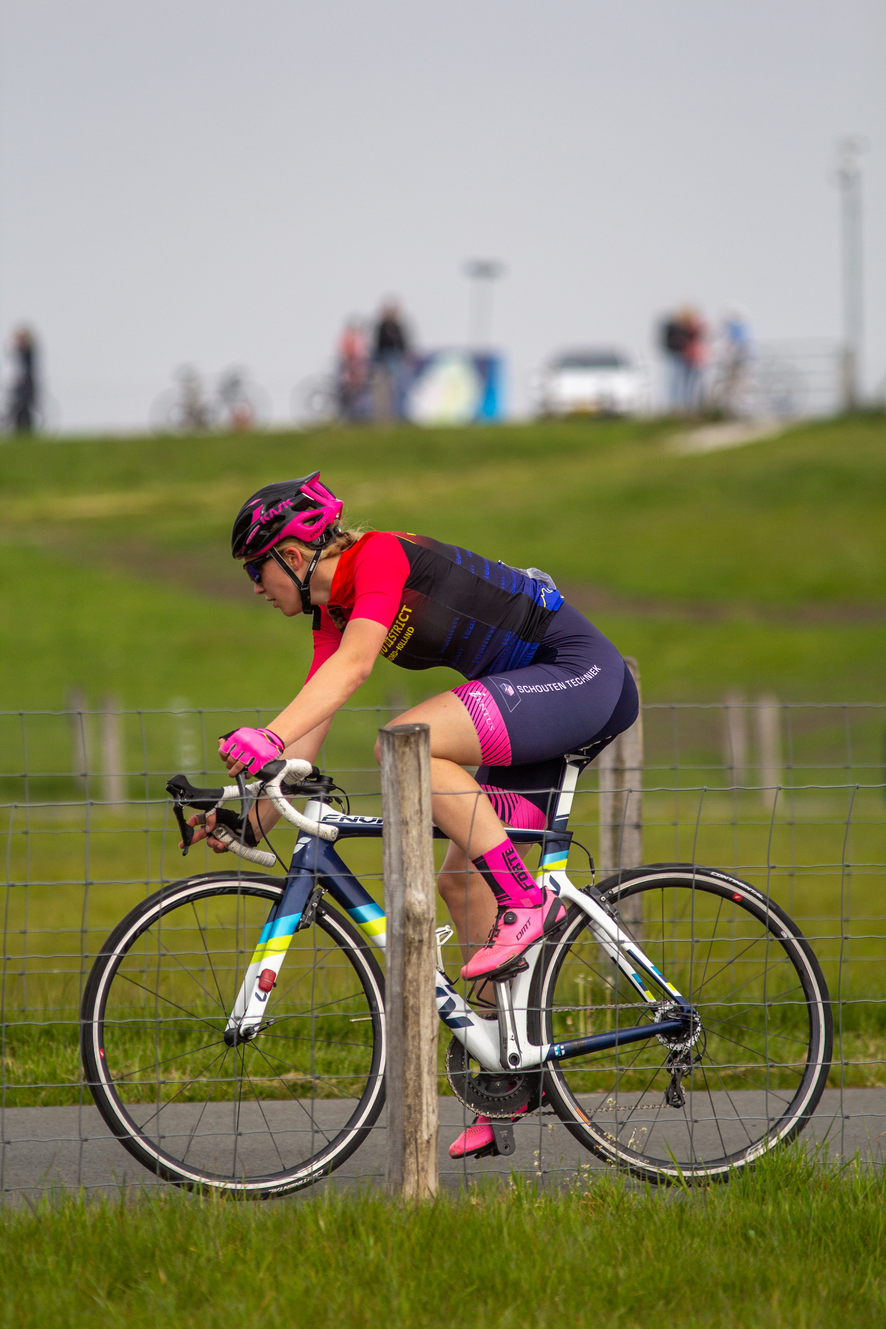 A woman wearing a pink helmet is riding a bicycle.