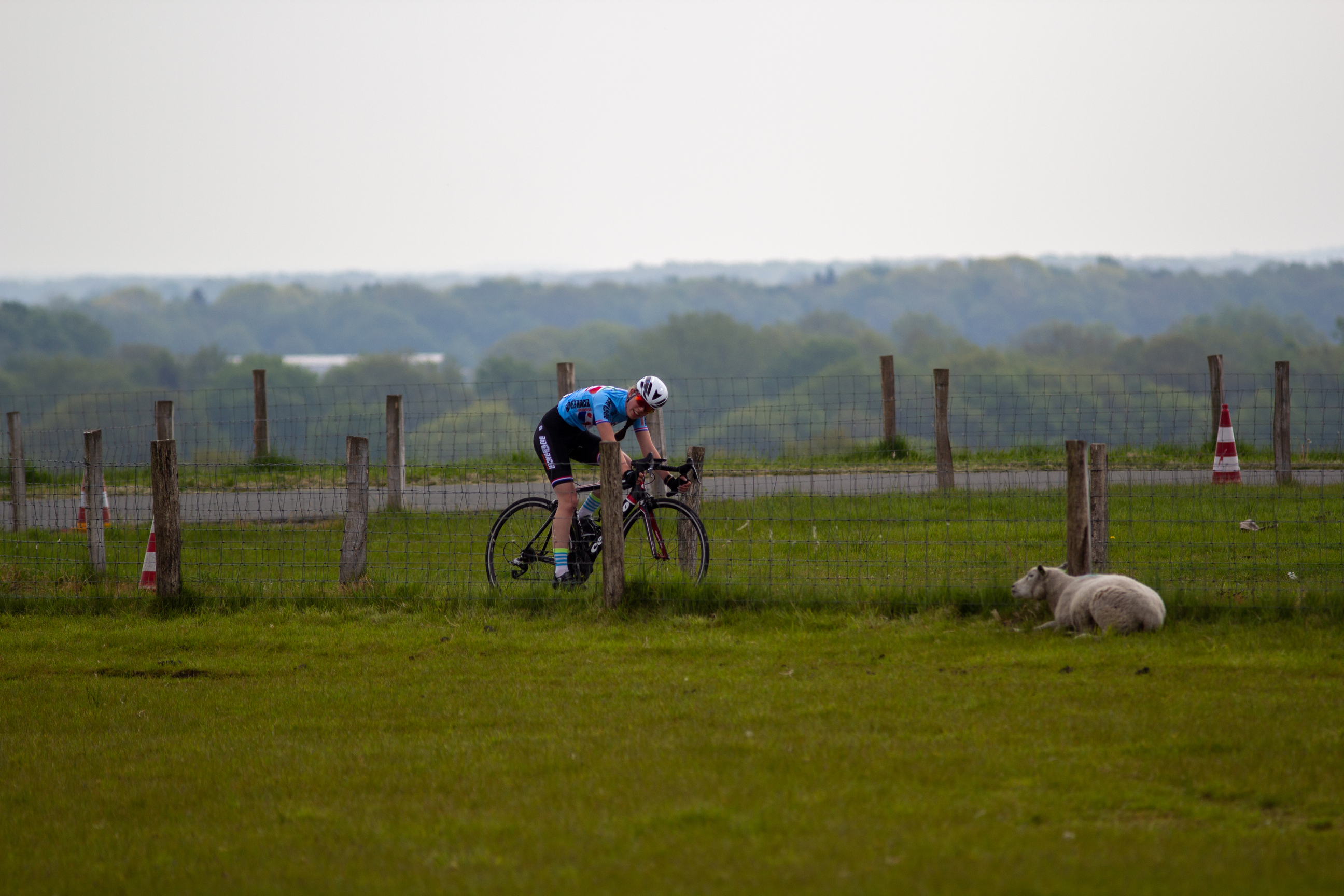 A man in a blue shirt races his bicycle around the corner of the course.