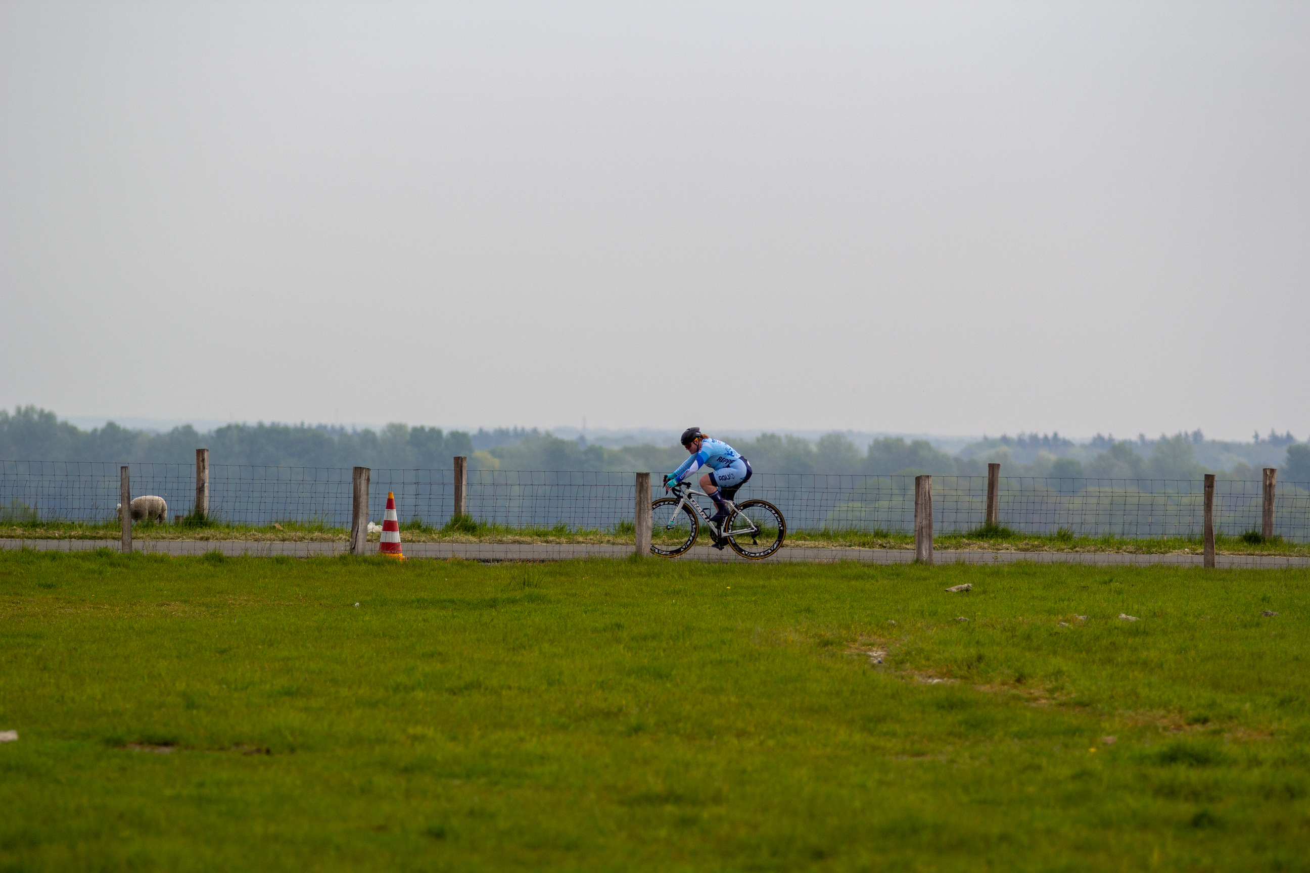 A person is riding a bike around cones in a grassy field.