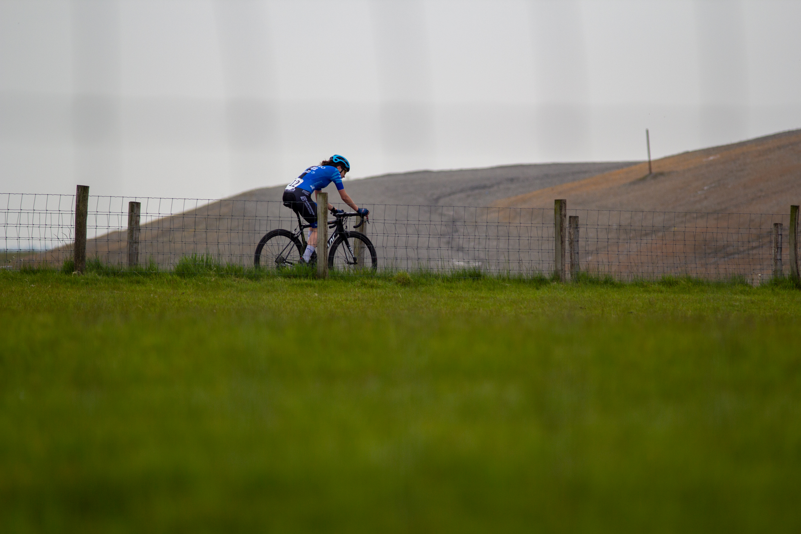 A woman on a bike wearing a blue shirt and a helmet.